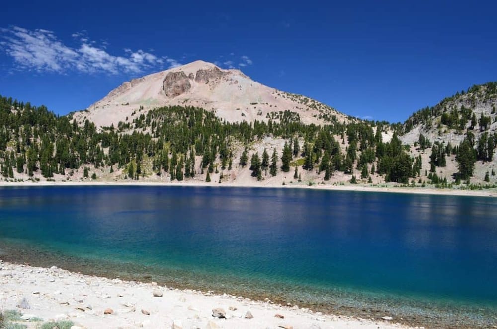 Serene mountain lake surrounded by pine trees and rugged landscape, perfect for outdoor adventure and nature exploration.