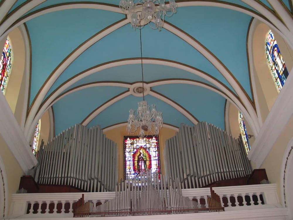 Ornate church interior with colorful stained glass windows and large pipe organ.