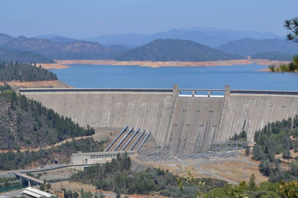 Giant dam with water reservoir and mountain landscape, showcasing engineering and nature.