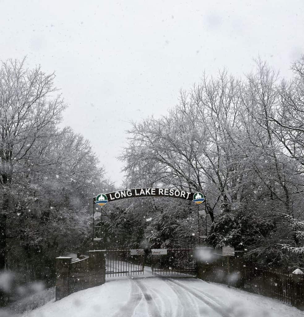 Snowy entrance to Long Lake Resort with winter landscape and snow-covered trees.