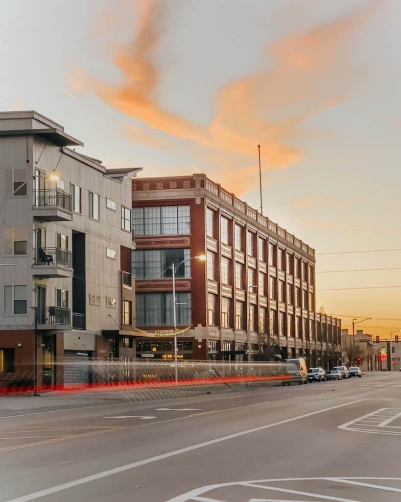 Bright city buildings during sunset with street traffic, urban landscape, and clear sky.