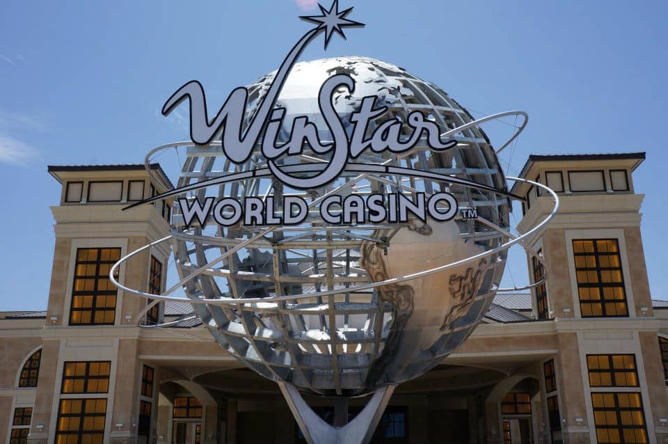Large metallic globe with "Winstar World Casino" sign, iconic casino entrance, international gaming destination, Las Vegas style attraction.