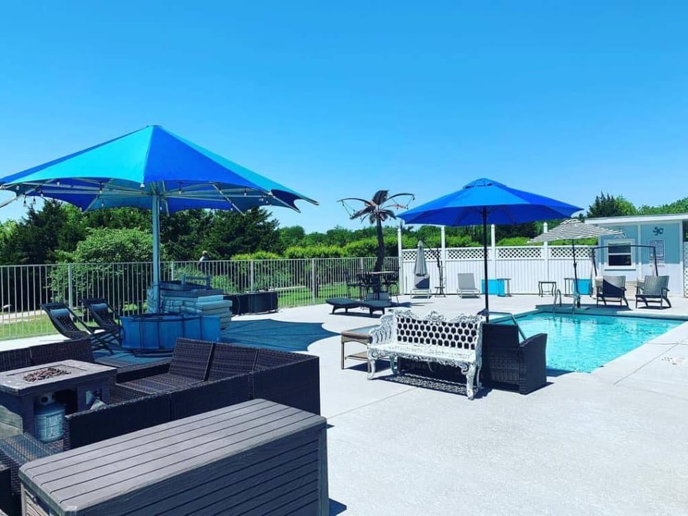 Modern outdoor pool area with lounge chairs, umbrellas, and greenery for relaxation and recreation.