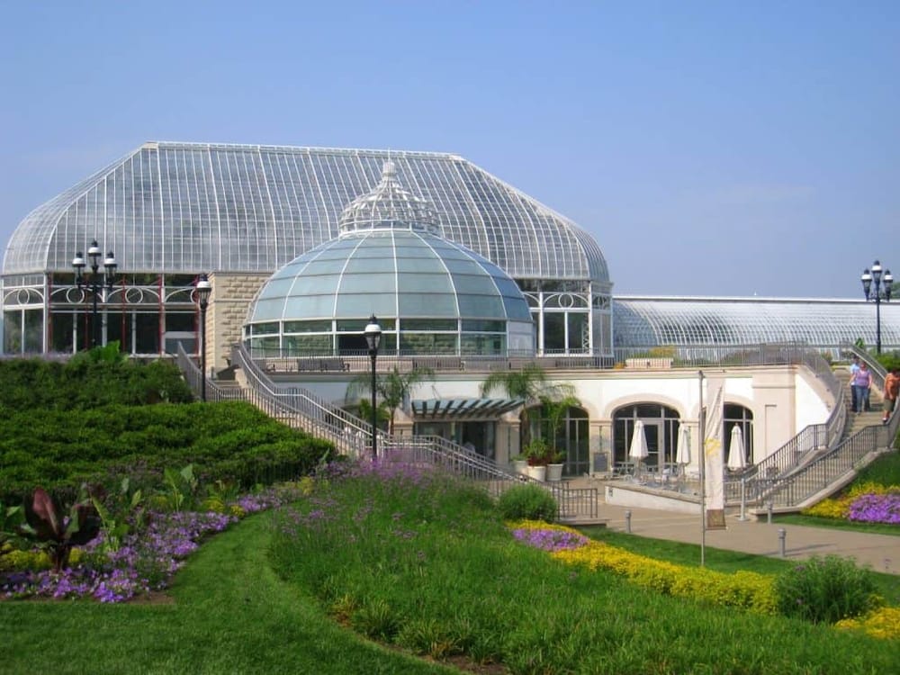 Beautiful botanical garden with glass greenhouse and vibrant flowers, perfect for relaxing and nature walks.