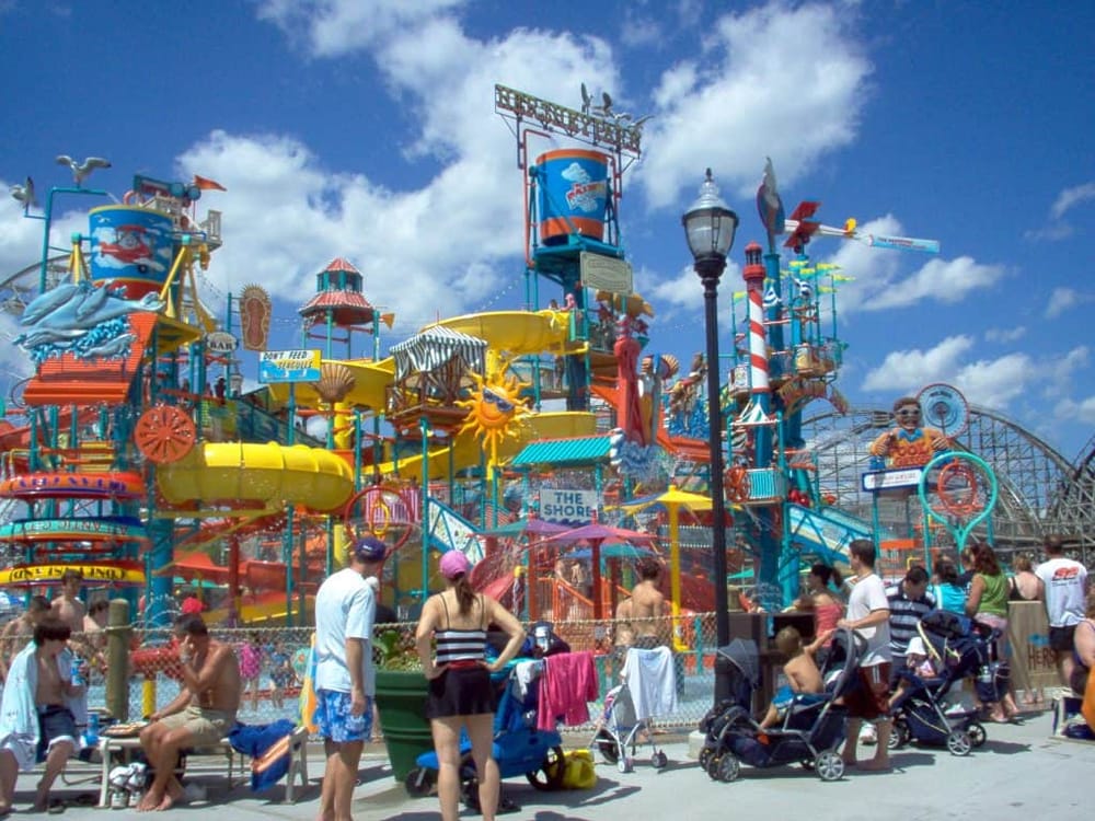 Colorful water park with slides and crowds enjoying a sunny day at the seaside.