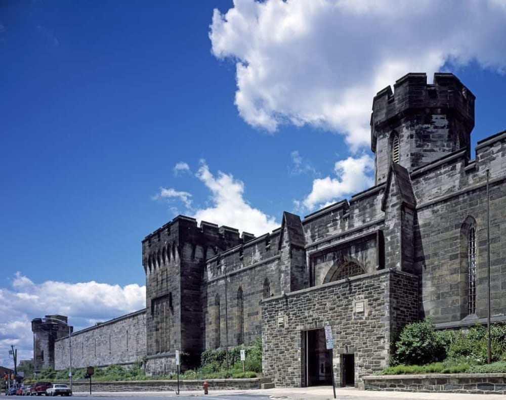 Ancient stone castle with tall towers under a bright blue sky with scattered clouds.
