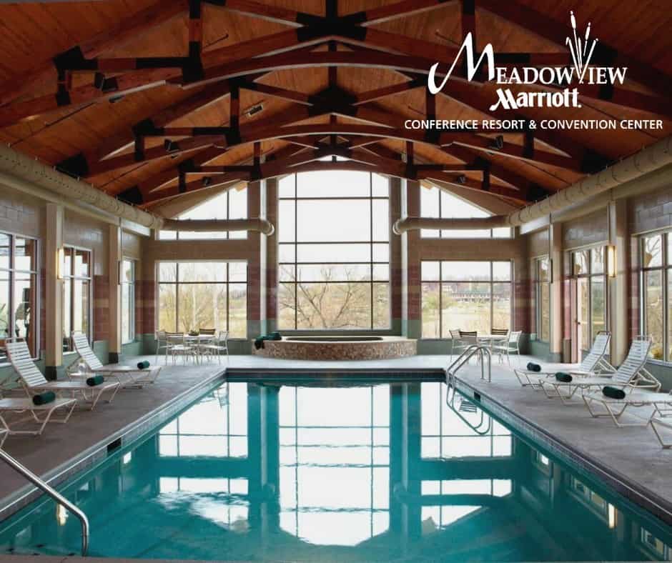 Indoor pool at MeadowView Marriott Conference Resort & Convention Center with large windows and relaxing lounge chairs.