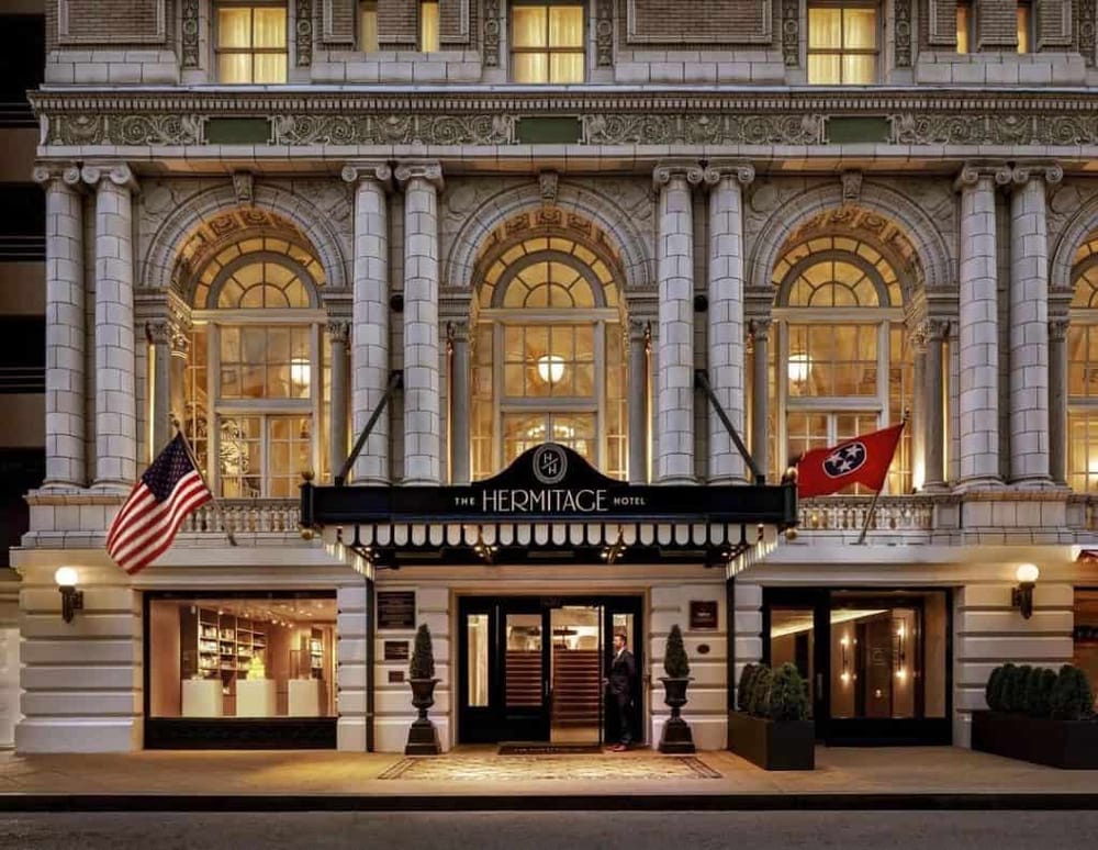 Luxury hotel entrance with historic architecture, American and Tennessee flags, and elegant exterior lighting.