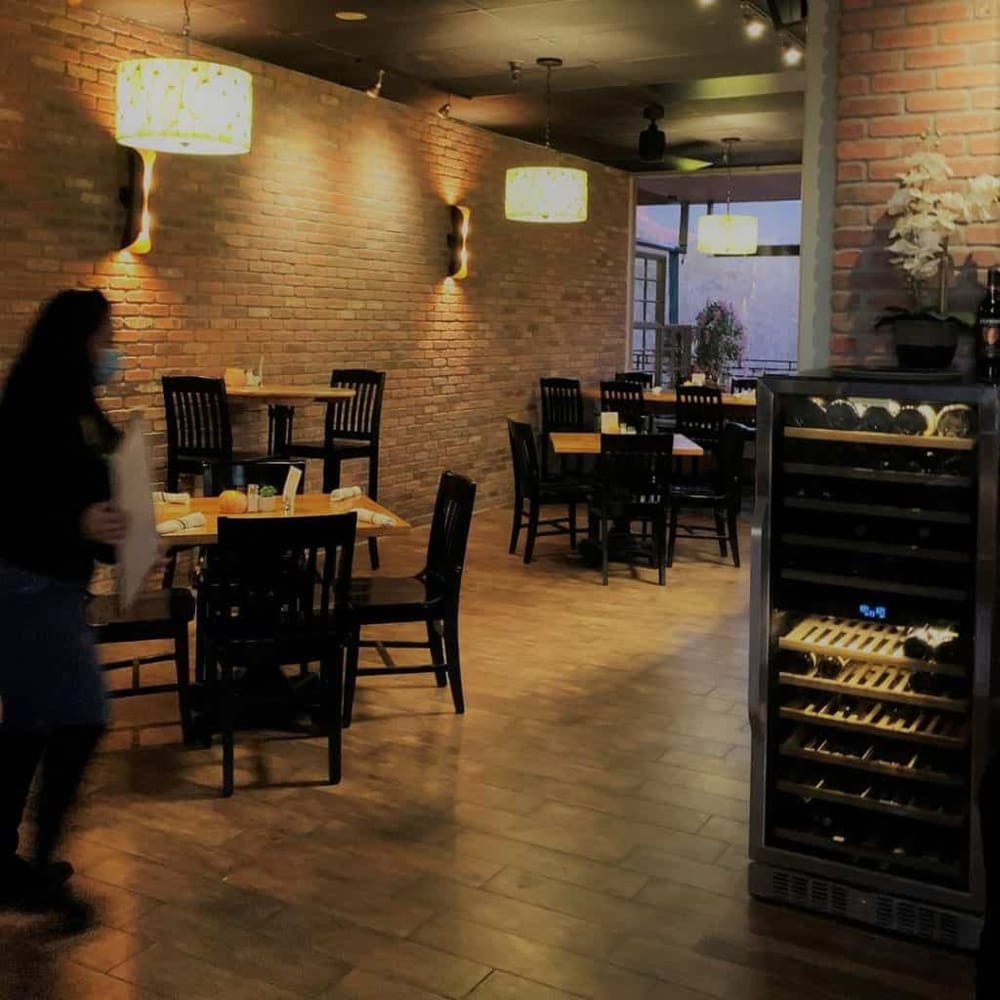 Cozy modern restaurant interior with brick walls, wooden floors, and ambient lighting for an inviting dining experience.