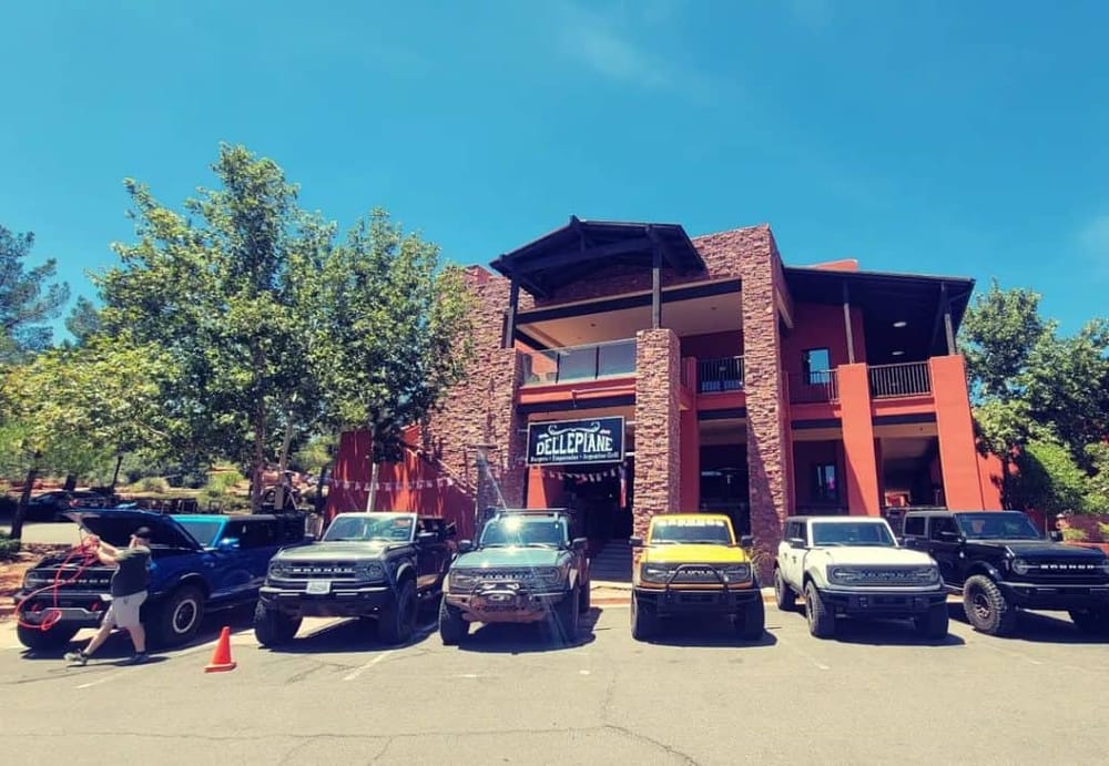 Modern building with parking lot and trucks, QuestForDirections signage, Arizona cuisine restaurant.