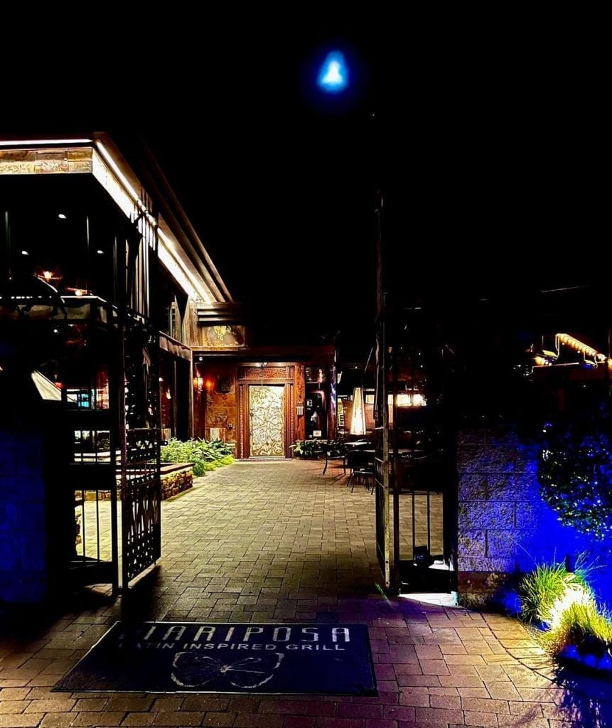 Cozy outdoor restaurant entrance at night with illuminated decor and seating area, perfect for dining and socializing.
