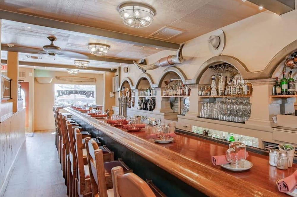 Cozy restaurant bar interior with wine glasses and liquor bottles, inviting atmosphere for dining and drinks.