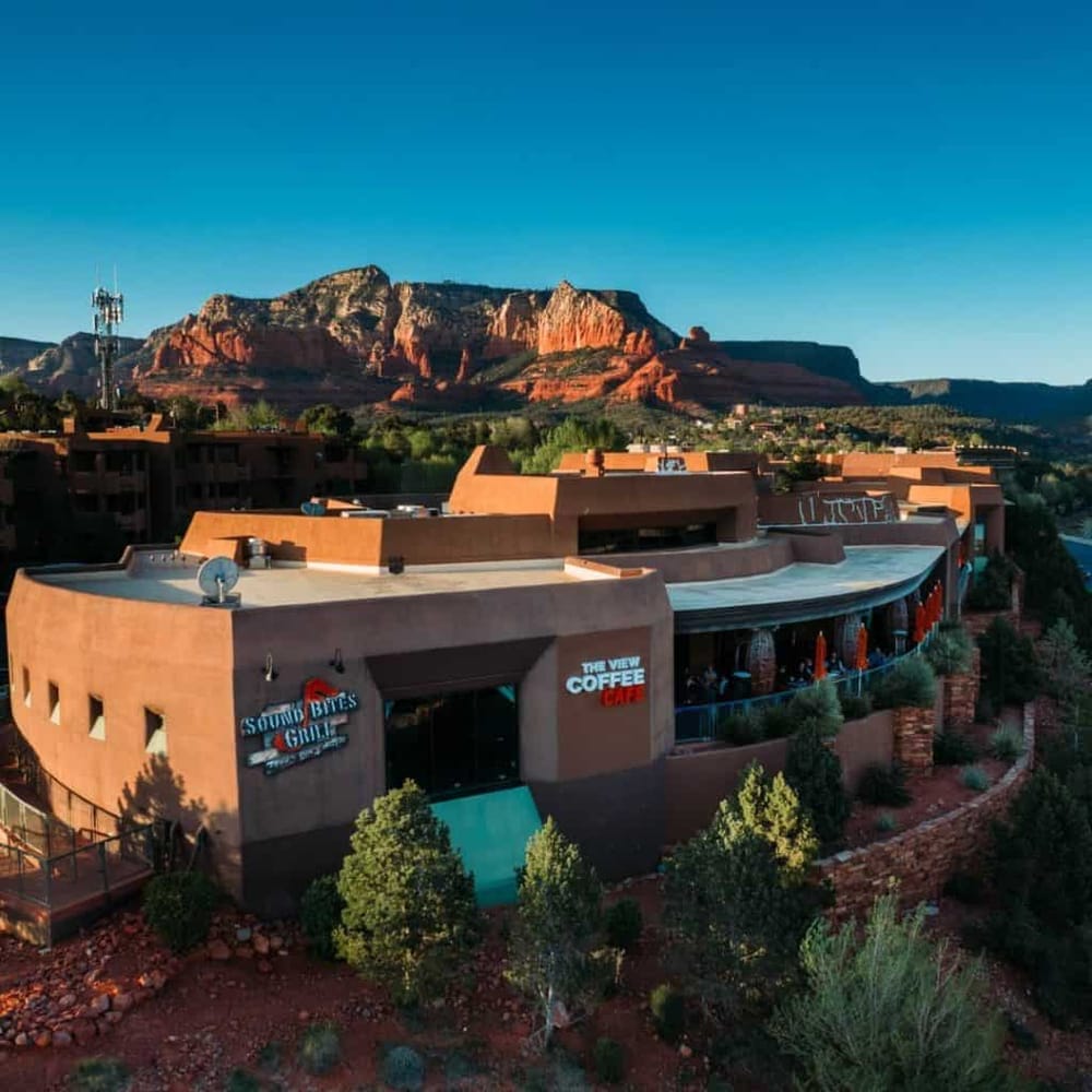 Vibrant desert landscape with modern building and red rock mountains in the background.