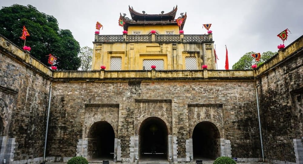 Ancient Vietnamese citadel gate with colorful flags and traditional architecture.