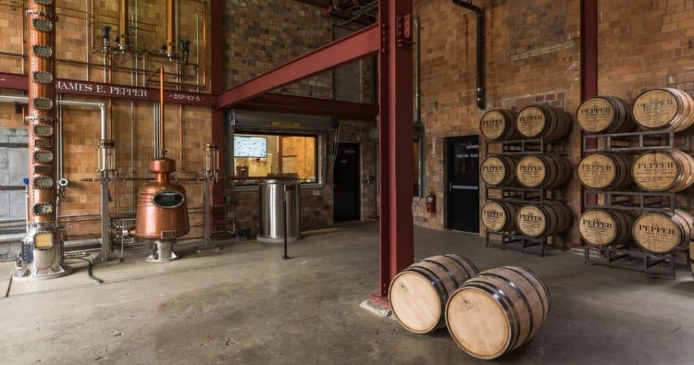 Copper distillery equipment with whiskey barrels at QuestForDirections distillery.