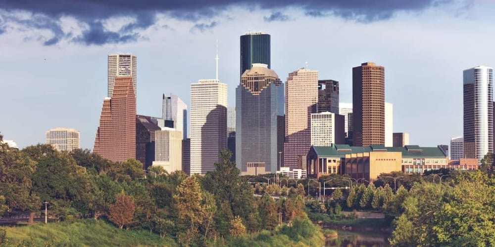 Skyscrapers and modern buildings of Los Angeles downtown skyline with lush green park foreground.