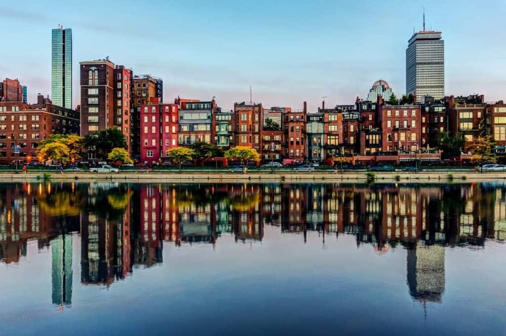 Colorful Boston waterfront with modern buildings reflected in the river, showcasing cityscape and urban scenery.