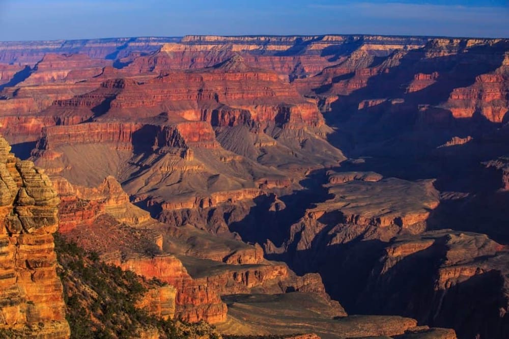 Vast Grand Canyon landscape during daytime with colorful rock formations and deep valleys.