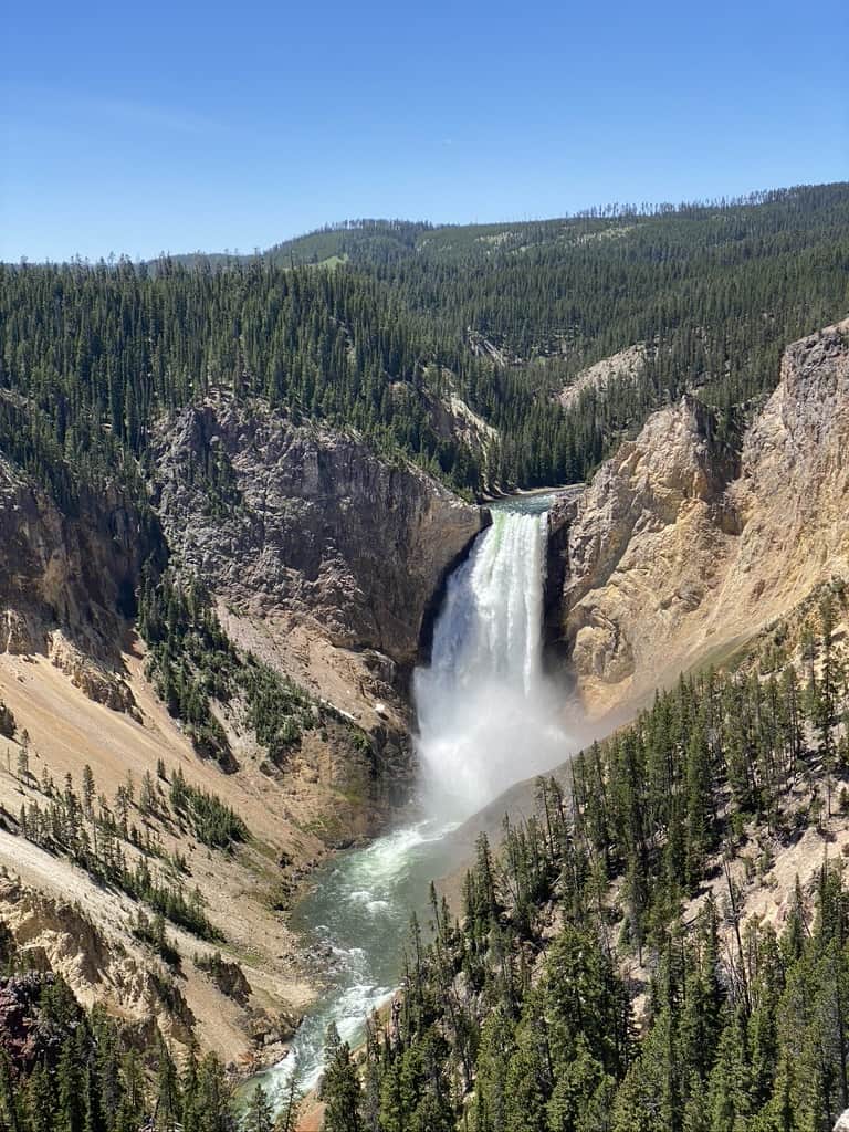 Breathtaking view of a waterfall cascading in a forested canyon, representing adventure and scenic landscapes.
