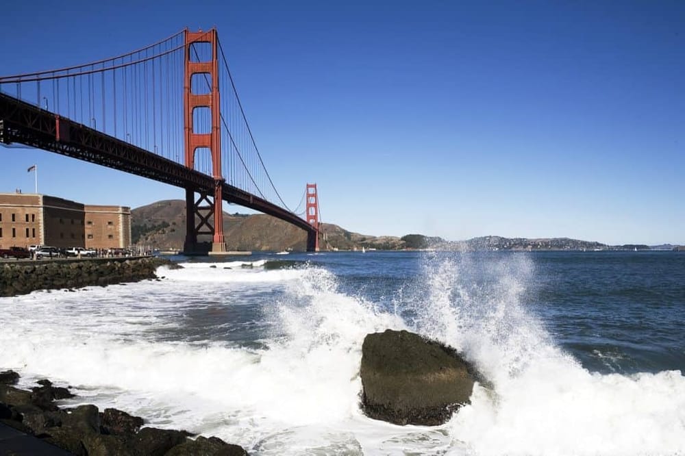 Golden Gate Bridge in San Francisco with ocean waves crashing, iconic California landmark, scenic coastal view, popular travel destination.