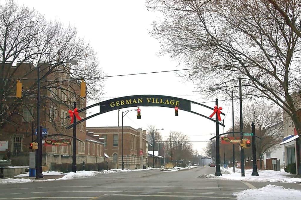 Charming German Village entrance decorated for Christmas with bows and lights in a snowy town scene.