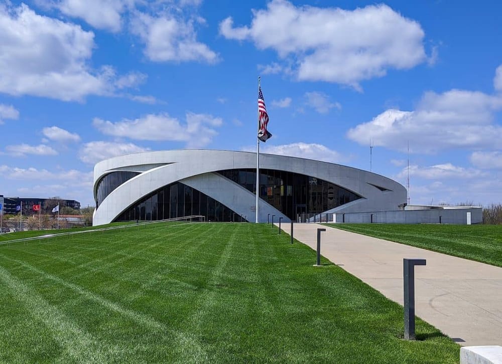 Modern performing arts center with a curved white façade and an American flag on a sunny day.