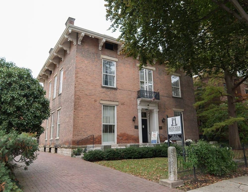 Historic brick house at Kelton House Museum & Gardens, showcasing classical architecture and lush surrounding greenery.