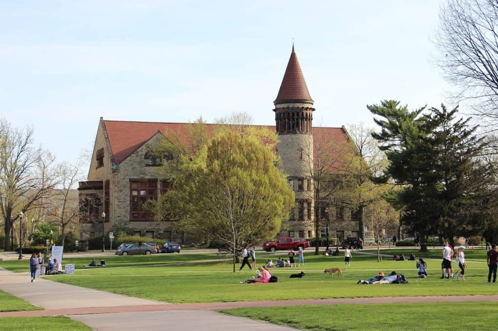 Historic university building with a castle-like tower in a lush park setting, popular for student gatherings and community events.