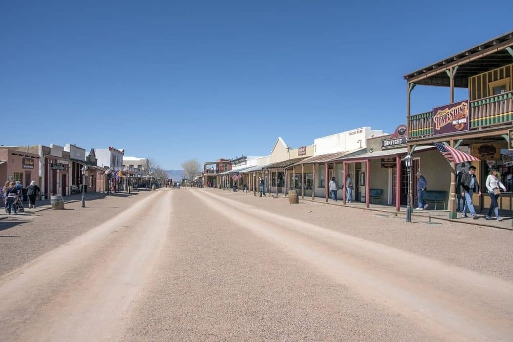 Old West themed amusement park street with storefronts and visitors, perfect for family fun and adventure.