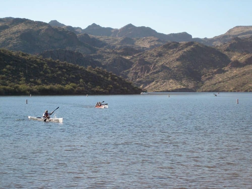 Kayakers on scenic lake with mountain backdrop in Arizona outdoor adventure.