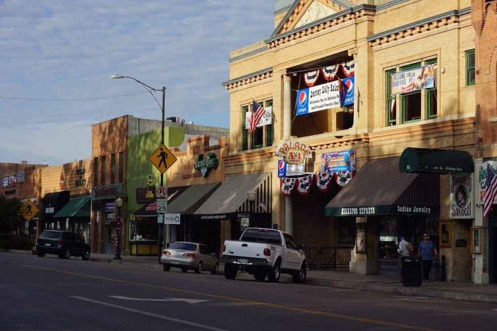 Colorful downtown main street with historic buildings, shops, and banners for local events, captured during daylight.