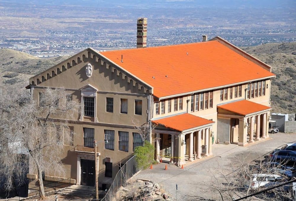 Historic building with red tiled roof in a scenic mountain landscape.