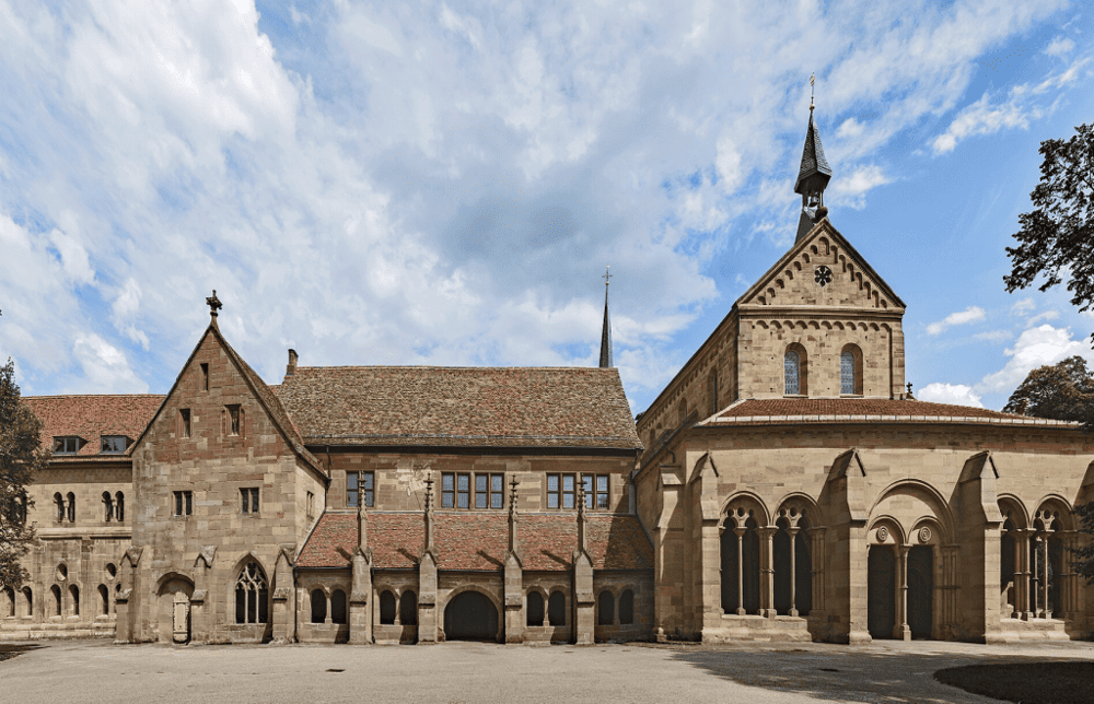 Historical stone church with Gothic architecture under blue sky and clouds.