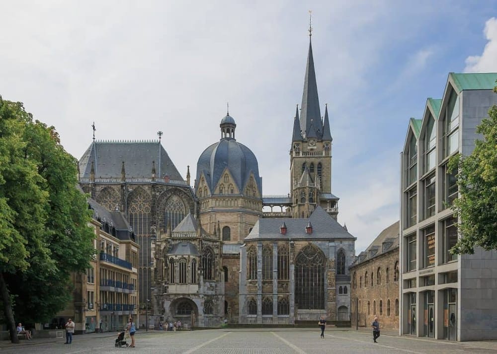 Historic Gothic church in the city center, surrounded by modern buildings and green trees.