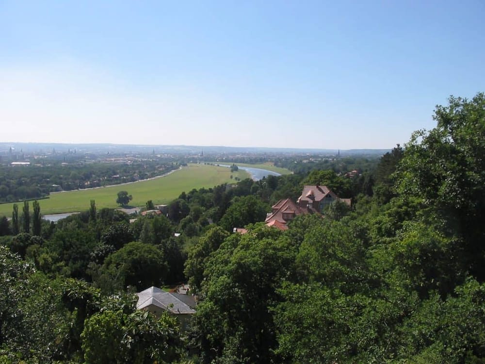 Breathtaking view of lush greenery, houses, and a winding river in a scenic natural landscape.