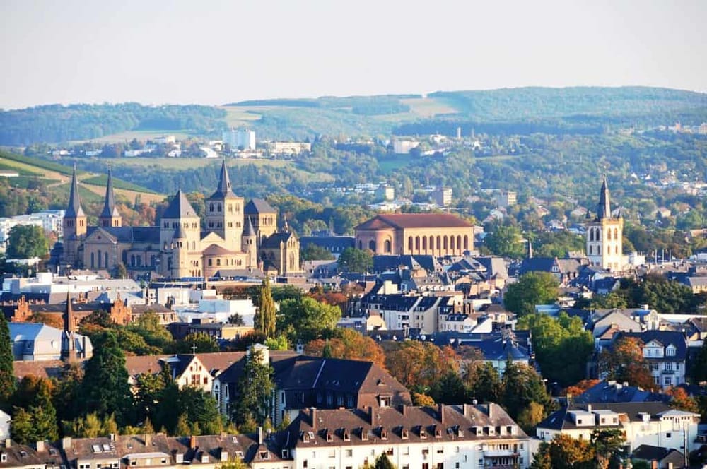 Scenic view of a historic European city with churches, rooftops, and surrounding green hills, showcasing travel destinations.