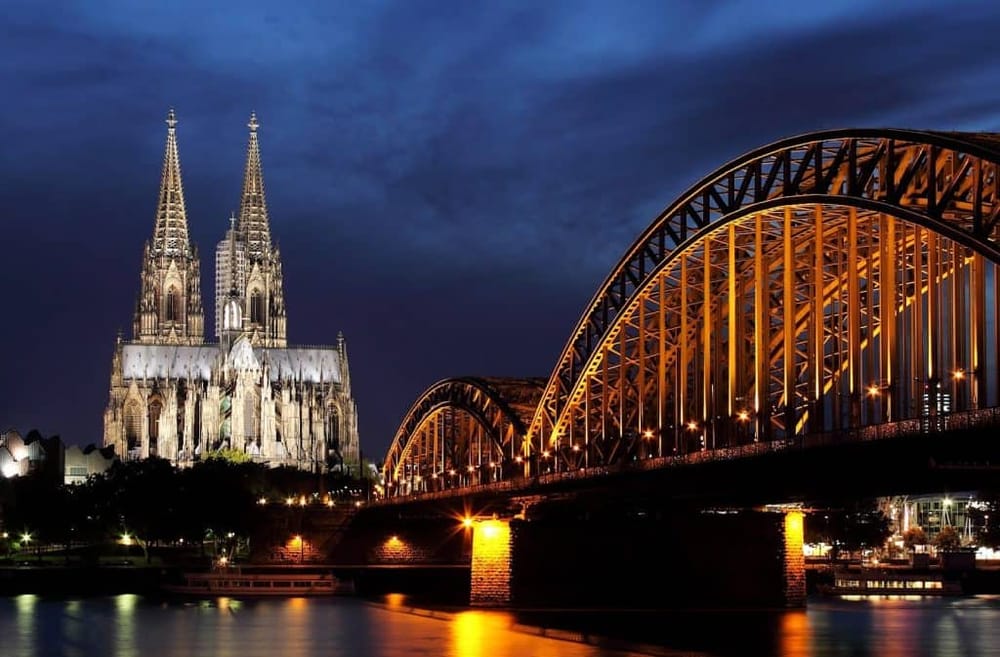 Magnificent Cologne Cathedral and Hohenzollern Bridge illuminated at night in Cologne, Germany.
