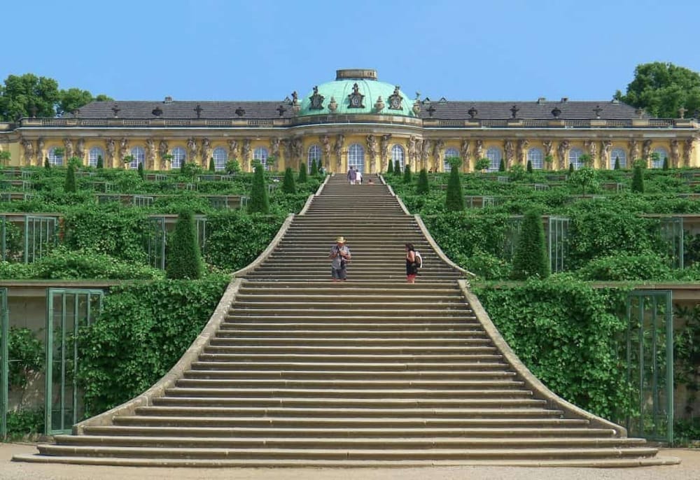 Lavish Baroque-style palace with grand staircase and lush green gardens, perfect for history buffs and architecture enthusiasts.