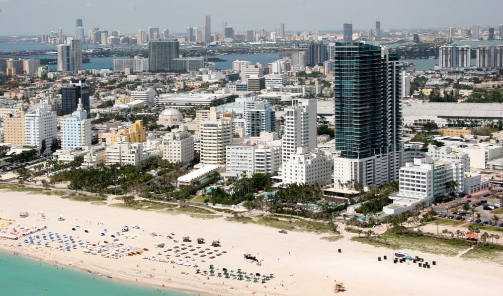 Modern Miami Beach skyline with sandy beach and ocean view at sunset.