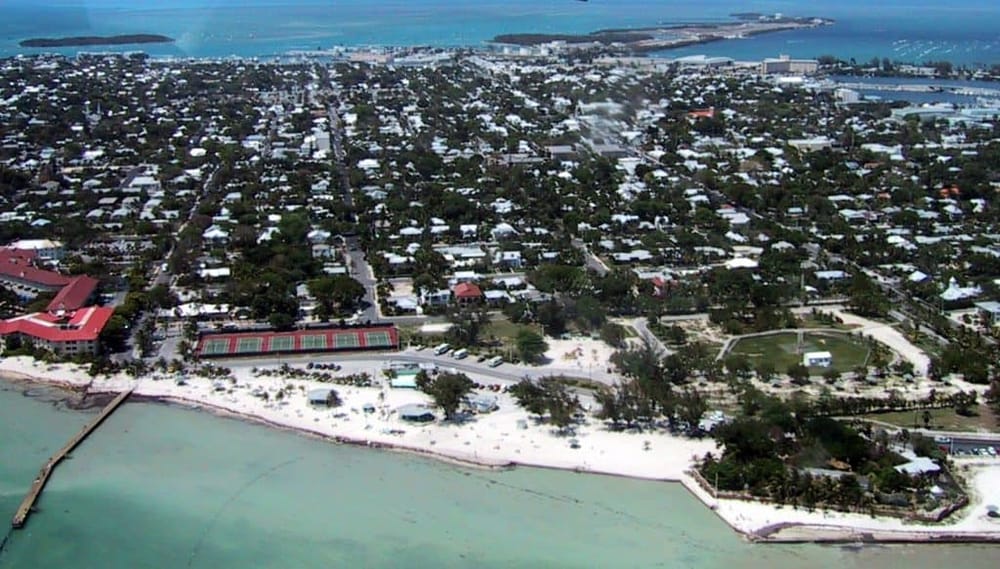 Aerial view of a coastal city with residential neighborhoods, beach, and marina, highlighting scenic seaside living.