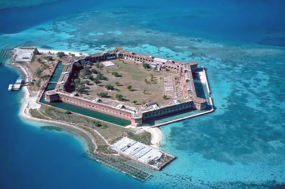 Aerial view of a historic island fort surrounded by clear blue waters.