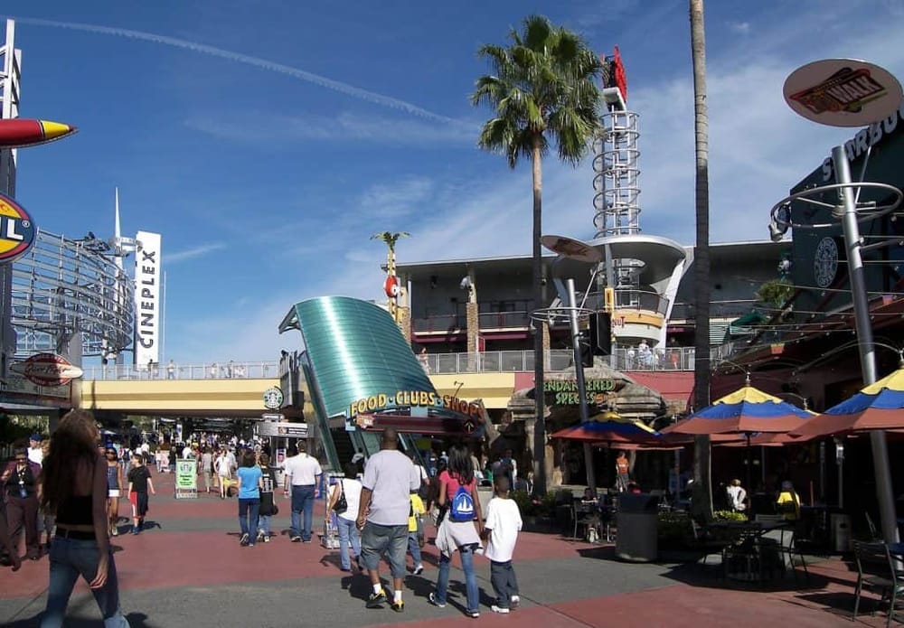 Thrilling amusement park scene with visitors enjoying rides and attractions, vibrant atmosphere and clear blue sky.