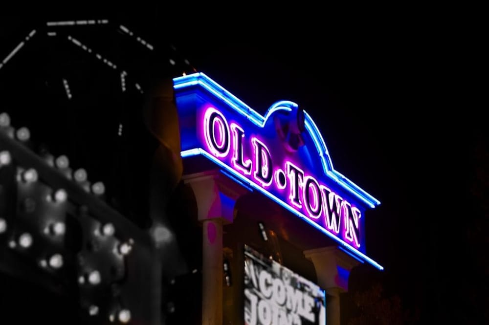 Neon Old Town sign illuminated at night, vibrant purple and blue glow, classic American nightlife atmosphere.
