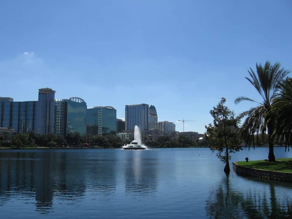 City skyline with lake and fountain in downtown Orlando, Florida, showcasing modern architecture and scenic park views.