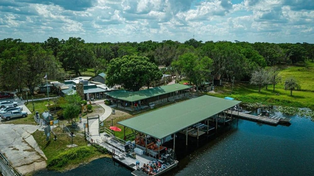 Scenic waterfront restaurant with dock, outdoor seating, and lush greenery, offering a relaxing dining experience.