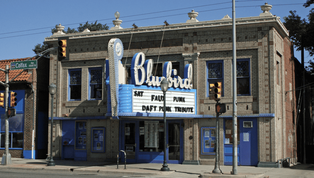 Vintage-style theater building with marquee signs in a city street.