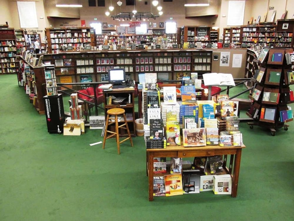 Brightly lit bookstore showcasing a wide selection of books, with multiple display tables and shelves filled with new releases and bestsellers.