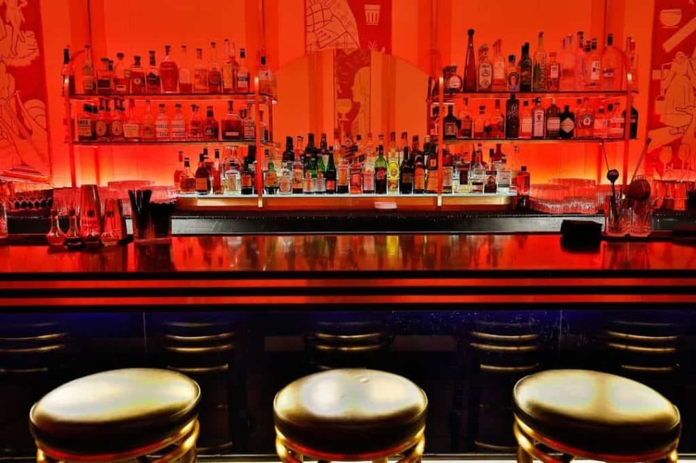 Luxurious bar with colorful Liquor bottles and illuminated backlit shelves for a vibrant nightlife experience.