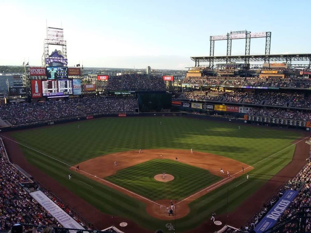 Vivid baseball game at Coors Field in Denver, Colorado, with cheering crowds and stunning city views.