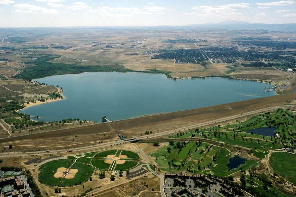 Aerial view of a scenic lake surrounded by parks, green spaces, and city landscape.